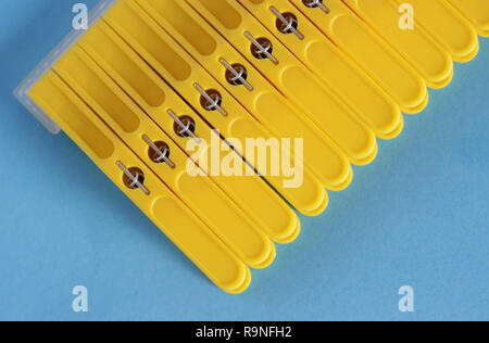 Yellow clothes pins isolated on blue background Stock Photo