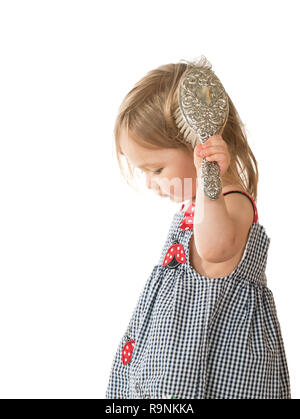 Cute young caucasian girl brushing hair with old hairbrush Stock Photo