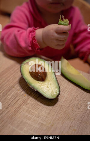 Children's hand reaches for the avocado. healthy food for children Stock Photo