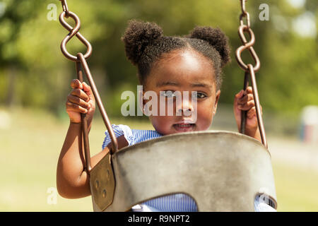 Cute little African American swinging at the park. Stock Photo