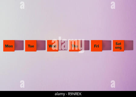 Monday, Tuesday, Wednesday, Thursday, Friday, Saturday, Sunday . a red cube. Purple background. Stock Photo
