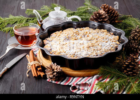 Traditional Christmas cake with dried fruits, raisins and a cup of tea on a wooden table with Christmas decorations Stock Photo