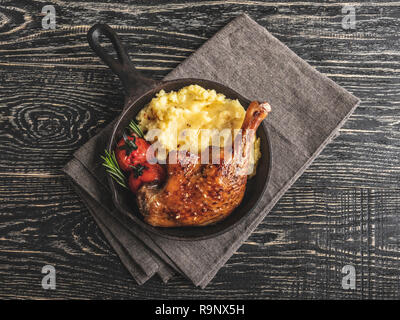 Juicy roasted duck leg with tomato, mashed potatoes in a serving fry pan Stock Photo