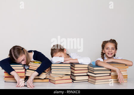 three girls schoolgirls at a desk with books on the lesson at school Stock Photo