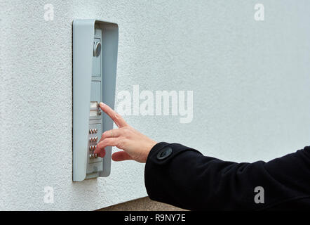 The female hand presses a button doorbell with camera and intercom Stock Photo