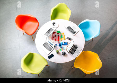 Top view on the working place with round table and colorful chairs in the office Stock Photo