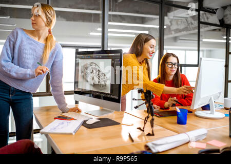 Group of young creative coworkers designing a car model at the working place with computers in the modern office interior Stock Photo
