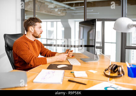 Portrait of a thoughtful man working with computer at the beautiful working place in the modern office interior Stock Photo