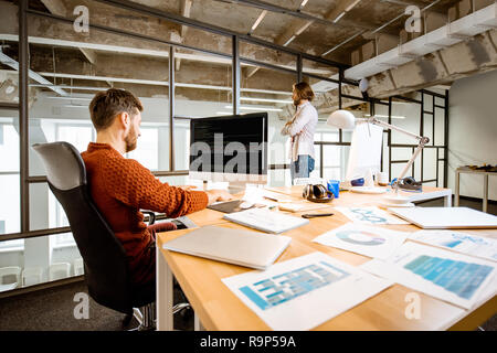 Man as a programmer working with computer code sitting at the beautiful working place in the modern office interior Stock Photo