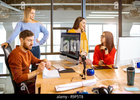 Group of a young coworkers dressed casually modeling 3d project working on computers in the modern office Stock Photo