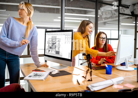 Group of a young coworkers working together on architectural project with computers in the modern office Stock Photo