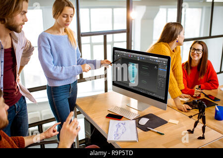 Group of a young coworkers dressed casually modeling 3d project working on computers in the modern office Stock Photo