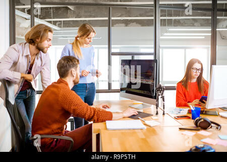 Team of a young programmers dressed casually working on computer code sitting in the modern office interior Stock Photo