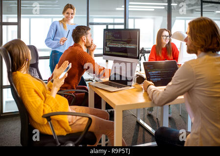 Team of a young programmers dressed casually working on computer code sitting in the modern office interior Stock Photo