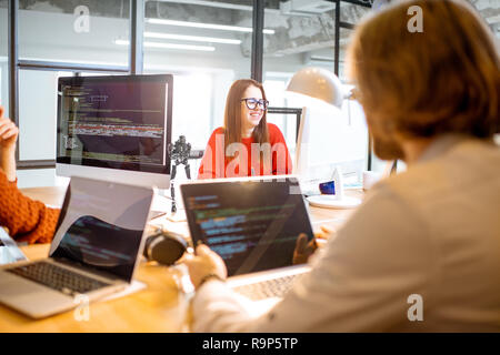 Team of a young programmers dressed casually working on computer code sitting in the modern office interior Stock Photo