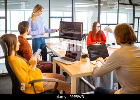 Team of a young programmers dressed casually working on computer code sitting in the modern office interior Stock Photo