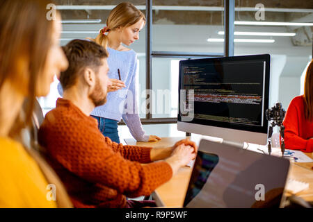 Team of a young programmers dressed casually working on computer code sitting in the modern office interior Stock Photo