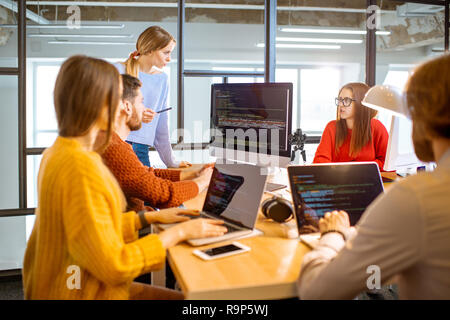 Team of a young programmers dressed casually working on computer code sitting in the modern office interior Stock Photo