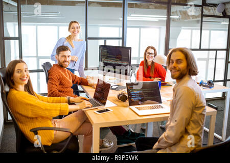 Portrait of a group of young programmers dressed casually working on computer code sitting in the modern office interior Stock Photo