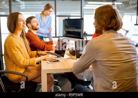 Team of a young programmers dressed casually working on computer code sitting in the modern office interior Stock Photo