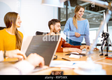 Team of a young programmers dressed casually working on computer code sitting in the modern office interior Stock Photo