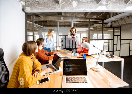 Team of a young programmers dressed casually working on computer code sitting in the modern office interior Stock Photo