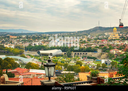 Tbilisi city landscape with famous landmarks. Bridge of peace, Concert Music Theatre Exhibition Hall and Holy Trinity Sameba church. View from the hil