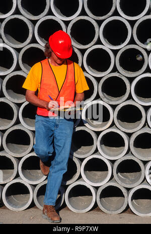 Construction worker leaning on cement pipes at worksite, USA Stock Photo