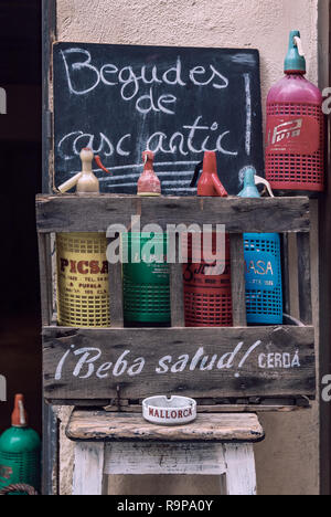 Colorful vintage soda bottles on display in a rustic wooden crate at a wine store with a Beba Salud brand name sign Palma de Mallorca, Spain Stock Photo