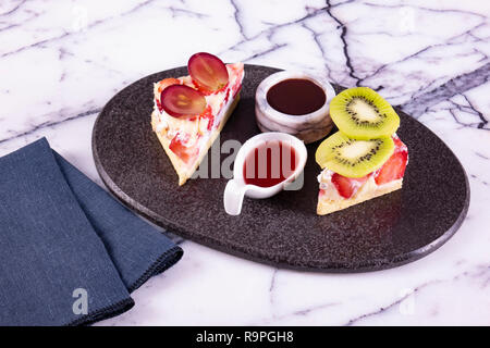 piece of cake on black plate with strawberries Stock Photo