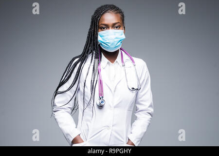 Close up of african female nurse wearing mask and hair net on gray background