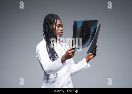 Young african Female doctor looking at an x-ray on gray background Stock Photo