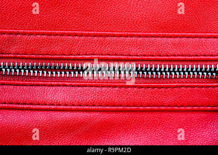 Zipper open between two layers of red fabric textile and red leather with visible seam under high magnification close detail photography as texture ba Stock Photo