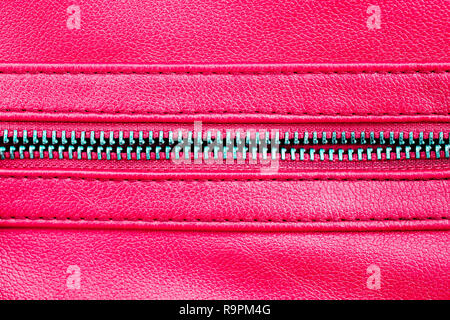 Zipper open between two layers of pink fabric textile and pink leather with visible seam under high magnification close detail photography as texture  Stock Photo