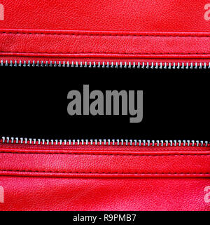 Zipper open between two layers of red leather fabric with visible seam under high magnification close detail photography as texture background with em Stock Photo