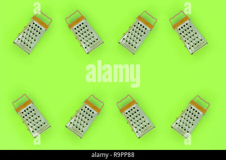 Small stainless steel graters lies on a pastel colored paper. Kitchen accessories. Tools for cooking. Flat lay top view. Stock Photo