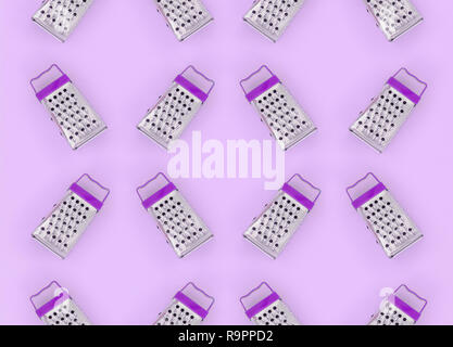 Small stainless steel graters lies on a pastel colored paper. Kitchen accessories. Tools for cooking. Flat lay top view. Stock Photo