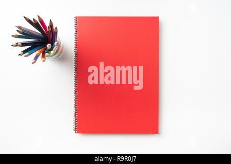 Design concept - Top view of  red spiral notebook and lot of pencils isolated on background for mockup Stock Photo