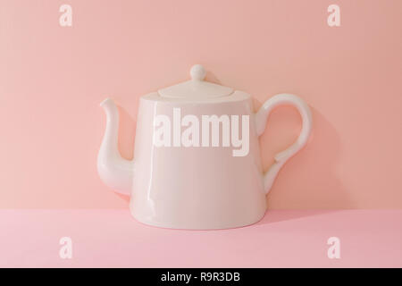 a ceramic white kettle. Pink Two Tone Background. Stock Photo