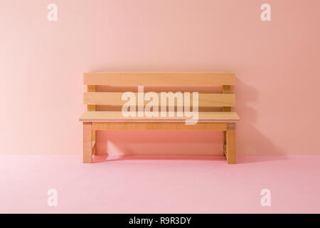 a wooden bench miniature. Pink Two Tone Background. Stock Photo