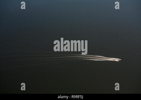 The motor yacht moves along the sea and leaves a mark on the water. View from above. Aerial. Stock Photo