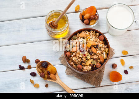 Granola cereal flakes with dried fruit, nuts and honey in a wooden bowl. Stock Photo