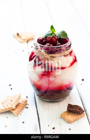 Sweet cherry cheesecake in a mason jar on wooden table Stock Photo