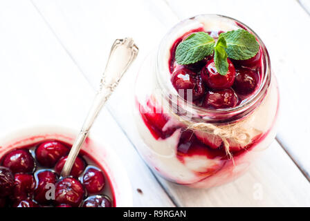 Sweet cherry cheesecake in a mason jar on wooden table Stock Photo