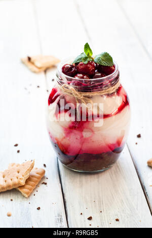 Sweet cherry cheesecake in a mason jar on wooden table Stock Photo