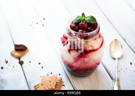 Sweet cherry cheesecake in a mason jar on wooden table Stock Photo