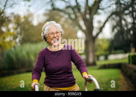 Happy senior woman walking with a walking frame. Stock Photo