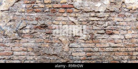 Old vintage dirty brick wall with peeling plaster texture background. Stock Photo