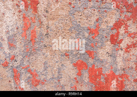 Old weathered painted wall background texture. Red dirty peeled plaster wall with falling off flakes of paint Stock Photo