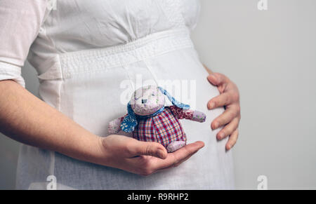 Belly of pregnant woman holding a baby rag doll Stock Photo